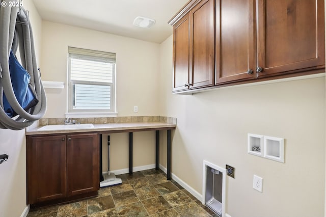 laundry room with baseboards, stone finish floor, a sink, cabinet space, and washer hookup