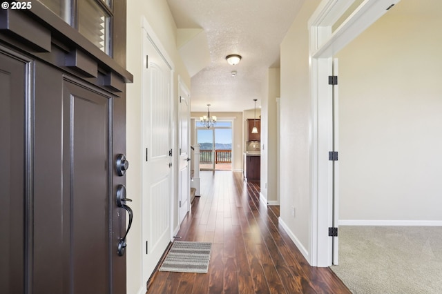 entrance foyer with an inviting chandelier, baseboards, dark wood finished floors, and a textured ceiling