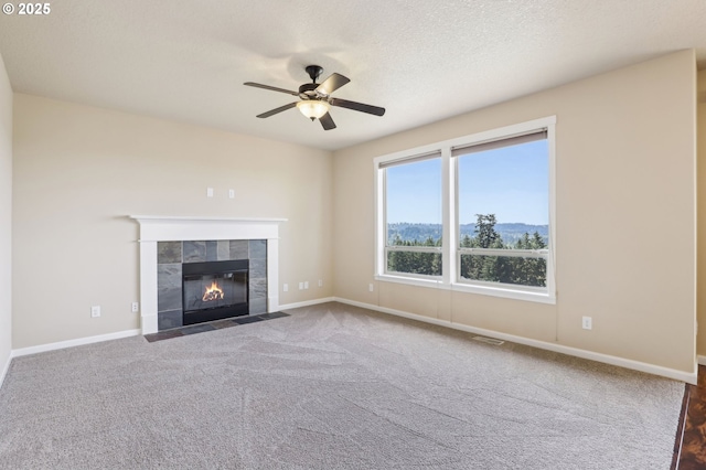 unfurnished living room with visible vents, a ceiling fan, baseboards, and a tiled fireplace