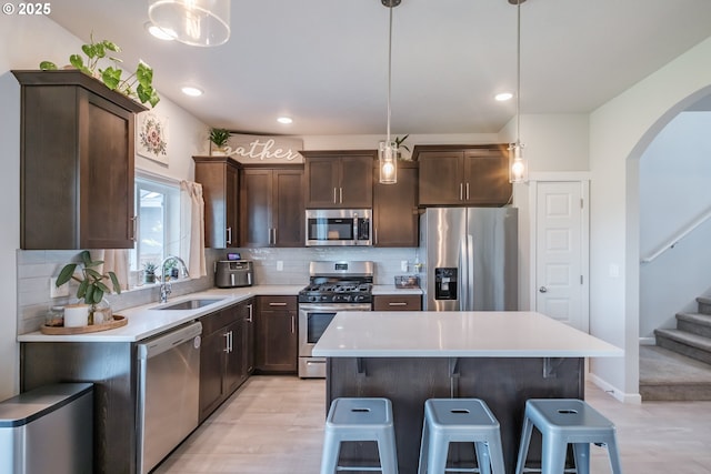 4507 Sagecrest Dr, Albany, OR 97322 - kitchen featuring stainless steel appliances, arched walkways, dark brown cabinetry, a breakfast bar, and backsplash