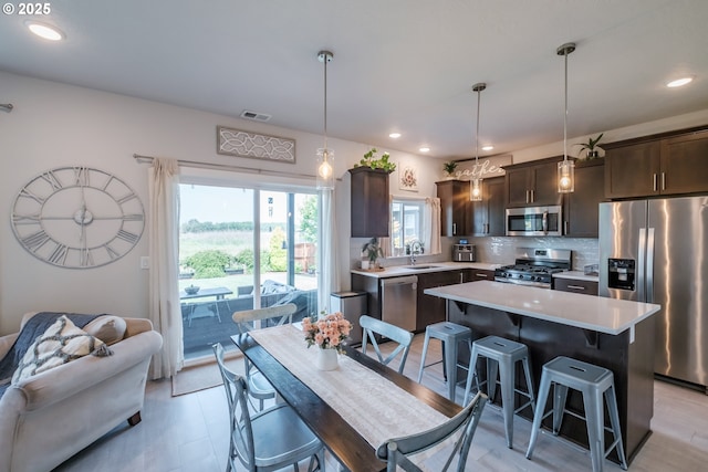 4507 Sagecrest Dr, Albany, OR 97322 - kitchen with stainless steel appliances, dark brown cabinets, light countertops, a kitchen breakfast bar, and decorative backsplash