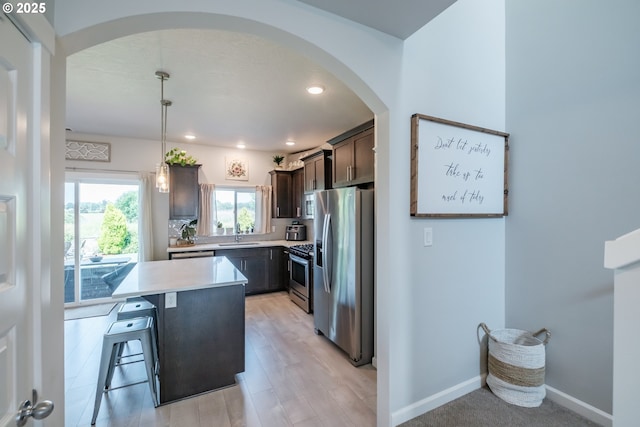 4507 Sagecrest Dr, Albany, OR 97322 - kitchen with stainless steel appliances, dark brown cabinets, arched walkways, light countertops, and a kitchen bar