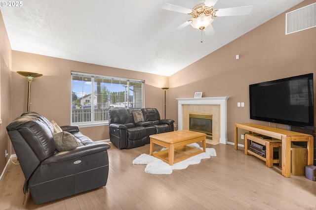 living room featuring lofted ceiling, baseboards, ceiling fan, wood finished floors, and a tile fireplace