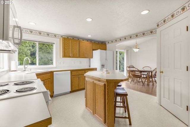 kitchen featuring white appliances, light floors, light countertops, a kitchen island, and recessed lighting