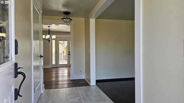 interior space with wood finished floors, a textured ceiling, baseboards, and an inviting chandelier