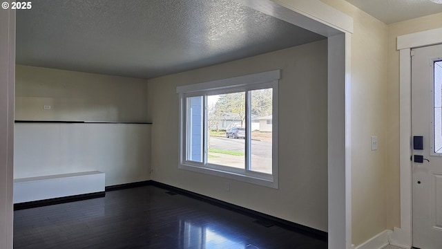 entryway featuring dark wood-style floors, visible vents, a textured ceiling, and baseboards