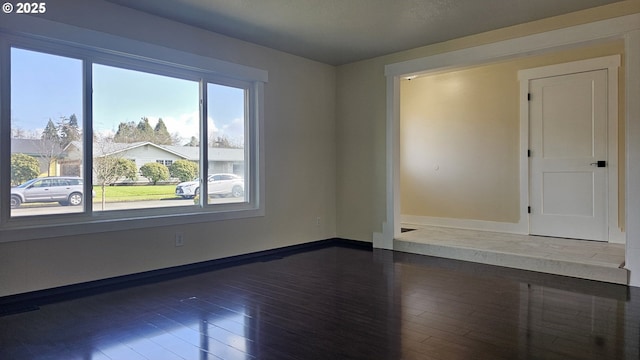 unfurnished room featuring dark wood-type flooring and baseboards