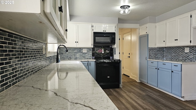 kitchen with dark wood finished floors, white cabinetry, a sink, light stone countertops, and black appliances