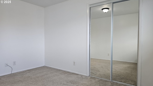 unfurnished bedroom with a closet, carpet flooring, and baseboards