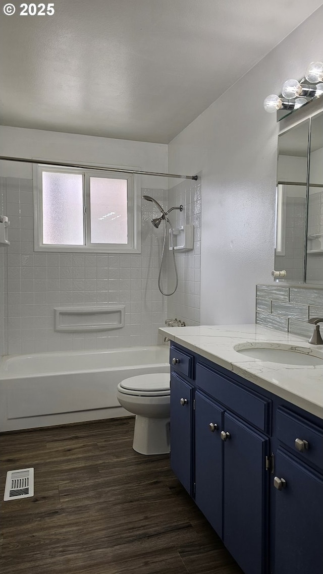 bathroom with visible vents, bathing tub / shower combination, toilet, wood finished floors, and vanity