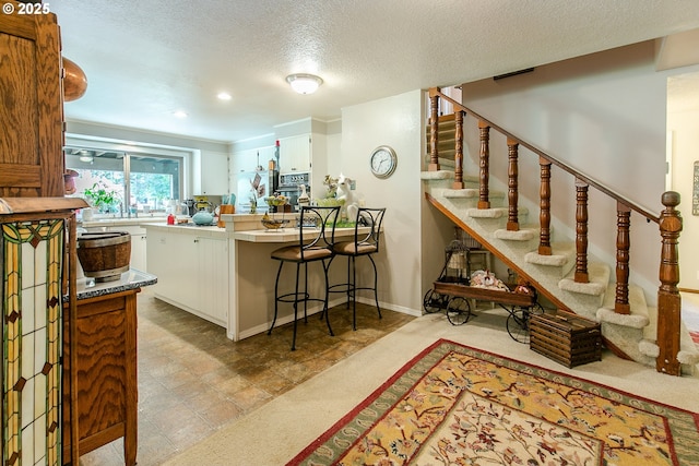 interior space featuring a peninsula, oven, a textured ceiling, a kitchen bar, and light countertops