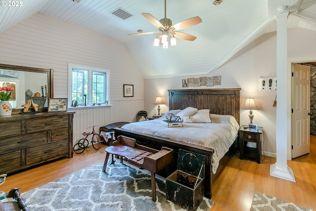 bedroom featuring wooden walls, wood finished floors, visible vents, and vaulted ceiling