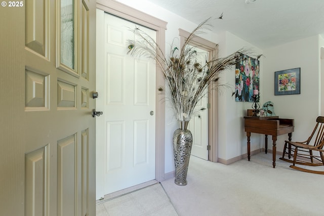 entrance foyer featuring light colored carpet and baseboards