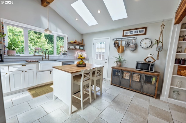12545 SW Fairfield St, Beaverton, OR 97005 - kitchen featuring stainless steel microwave, a skylight, a sink, open shelves, and white cabinetry