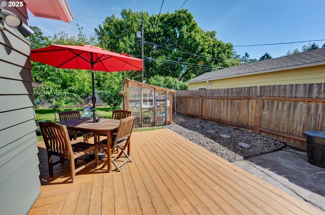 12545 SW Fairfield St, Beaverton, OR 97005 - wooden deck with a fenced backyard, outdoor dining space, a greenhouse, and an outbuilding