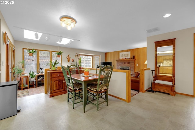 dining room with a brick fireplace and wood walls