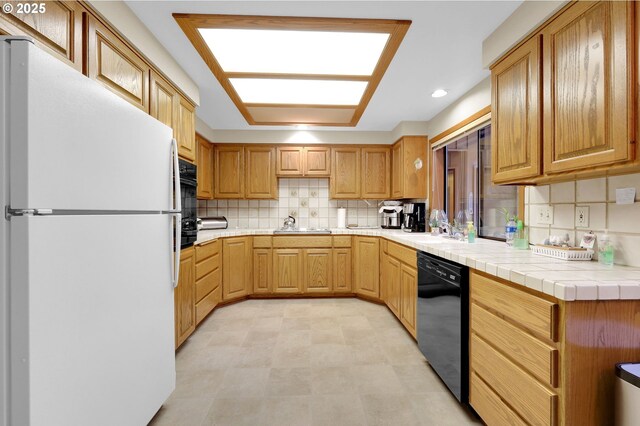 kitchen with sink, black appliances, tile counters, and tasteful backsplash