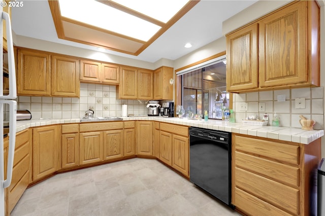 kitchen with tile counters, dishwasher, tasteful backsplash, and cooktop