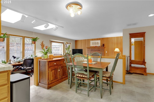 dining room with a skylight, wooden walls, and rail lighting