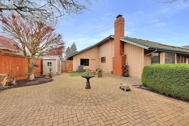 rear view of property with central AC unit, a storage shed, and a patio