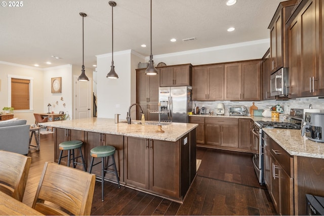 13372 SW Aubergine Ter, Sherwood, OR 97140 - kitchen with ornamental molding, a center island with sink, light stone counters, a sink, and appliances with stainless steel finishes