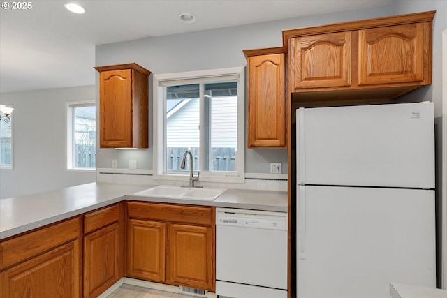 kitchen featuring an inviting chandelier, sink, white appliances, and kitchen peninsula