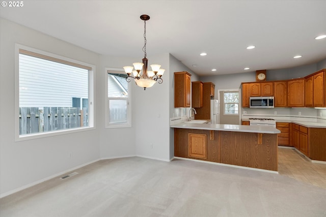 kitchen featuring sink, hanging light fixtures, a notable chandelier, kitchen peninsula, and white appliances