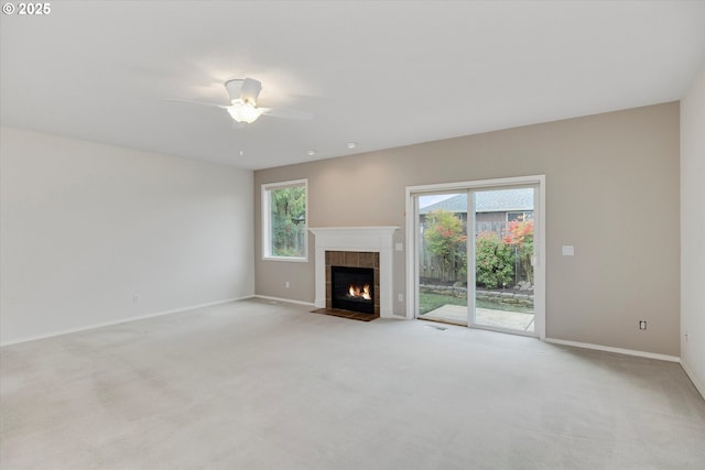 unfurnished living room featuring ceiling fan, a fireplace, and light carpet