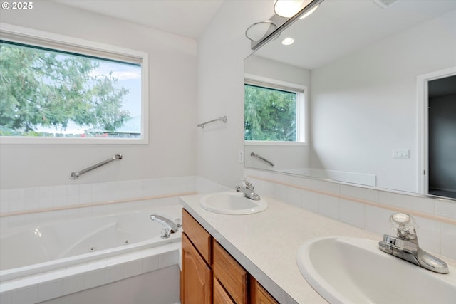 bathroom featuring a relaxing tiled tub and vanity