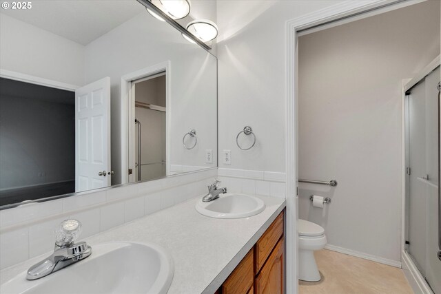 bathroom featuring vanity, a shower with shower door, and toilet