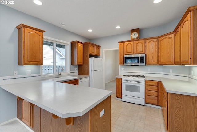 kitchen featuring white appliances, a breakfast bar, kitchen peninsula, and sink