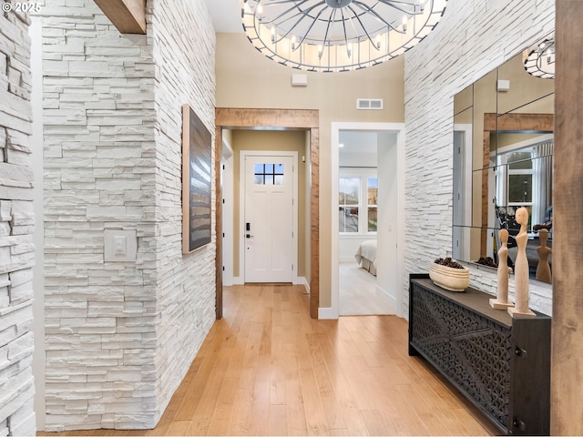 foyer entrance featuring hardwood / wood-style floors, a notable chandelier, and a towering ceiling