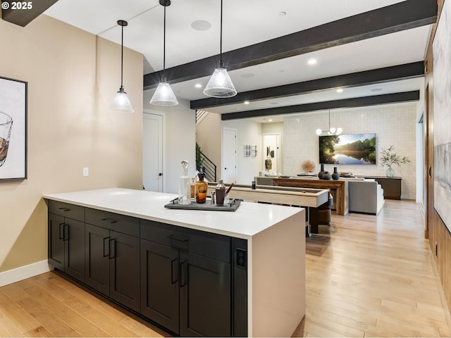 kitchen with hanging light fixtures, beam ceiling, and light hardwood / wood-style flooring