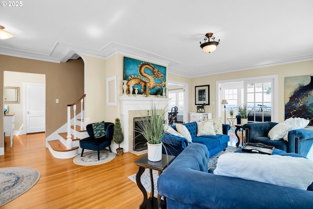 living room featuring light wood-style floors, ornamental molding, and a fireplace with flush hearth