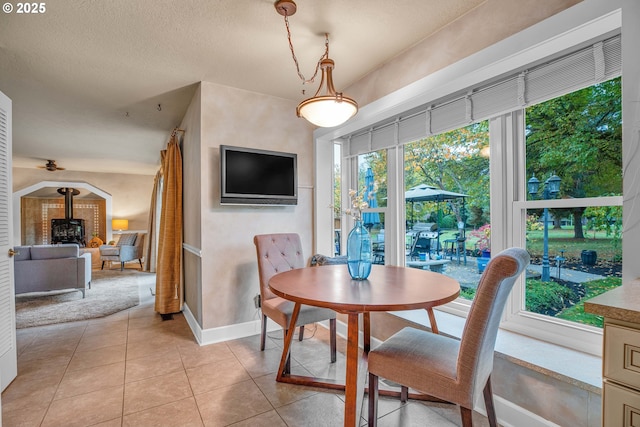 dining room featuring a wood stove, light tile patterned floors, and baseboards