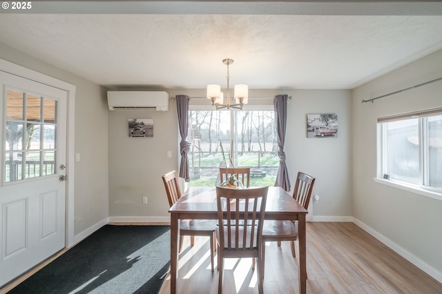 dining room with a notable chandelier, plenty of natural light, baseboards, and a wall mounted AC