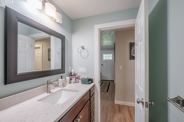 bathroom with vanity, wood finished floors, and baseboards