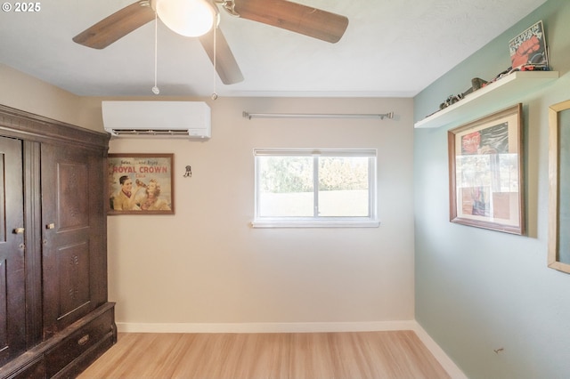 unfurnished bedroom with ceiling fan, baseboards, a wall unit AC, and wood finished floors