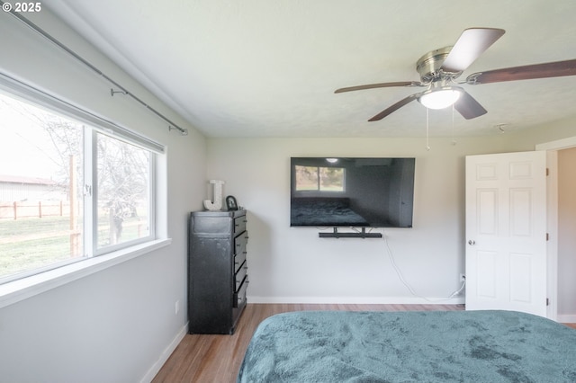 bedroom featuring baseboards, wood finished floors, and a ceiling fan