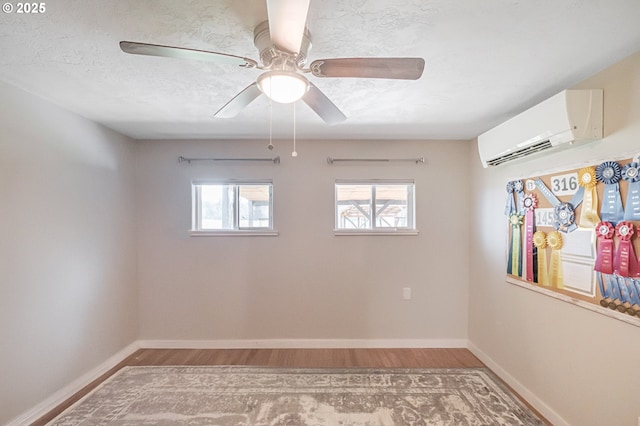 spare room with baseboards, a wall mounted AC, and light wood-style floors