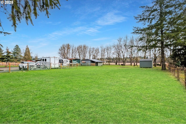 view of yard featuring an outbuilding, a storage unit, and fence