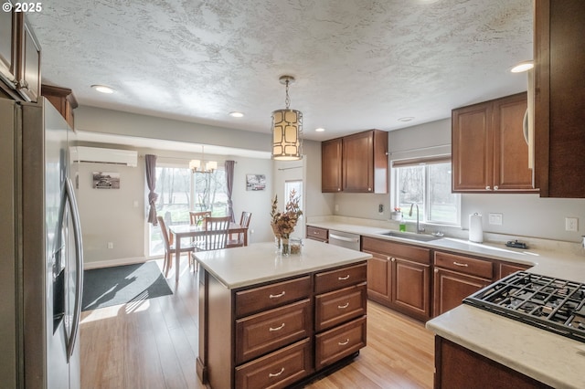 kitchen featuring light wood-style flooring, stainless steel appliances, a wall mounted AC, and a sink