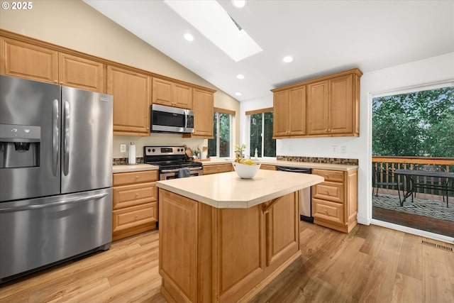 1573 SE 67th Ave, Hillsboro, OR 97123 - kitchen with stainless steel appliances, vaulted ceiling, a skylight, light wood finished floors, and light countertops