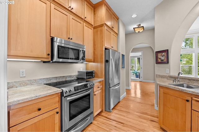 6420 SE Dunbar Dr, Portland, OR 97236 - kitchen with stainless steel appliances, arched walkways, light wood-style flooring, light stone counters, and recessed lighting