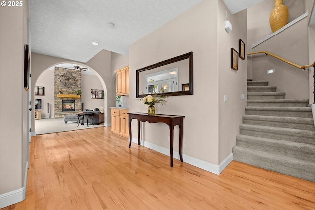 6420 SE Dunbar Dr, Portland, OR 97236 - entryway featuring light wood-type flooring, arched walkways, stairway, a fireplace, and ceiling fan