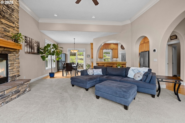 6420 SE Dunbar Dr, Portland, OR 97236 - living room featuring light colored carpet, a fireplace, ceiling fan, crown molding, and arched walkways