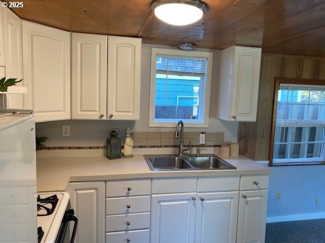 681 SE Neptune Ave, Lincoln City, OR 97367 - kitchen featuring a sink, range, white cabinets, and light countertops