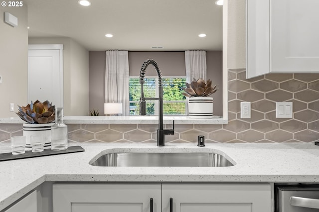 kitchen with light stone countertops, recessed lighting, a sink, white cabinets, and decorative backsplash