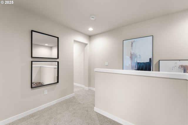 hallway with recessed lighting, light colored carpet, and baseboards