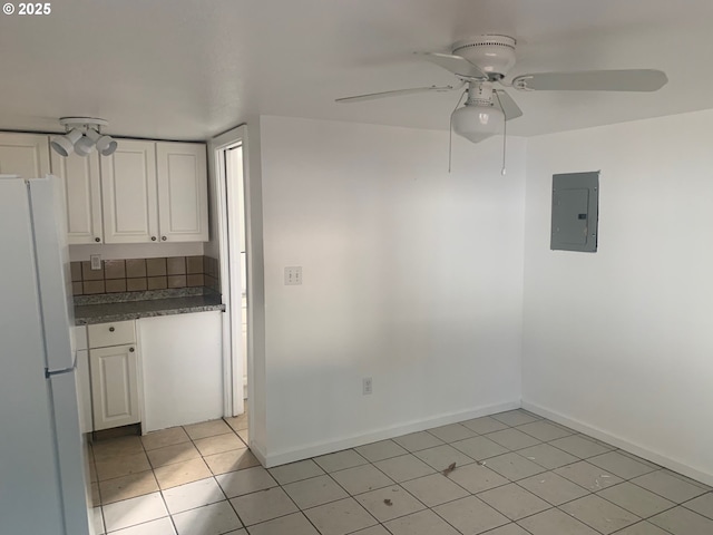 kitchen featuring electric panel, a ceiling fan, freestanding refrigerator, white cabinetry, and light tile patterned flooring